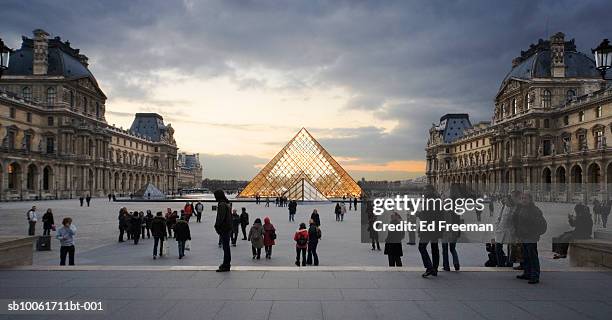 crowed outside louvre museum at sunset - louvre stock-fotos und bilder