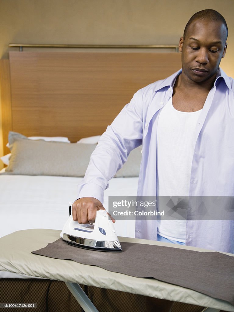 Businessman ironing trousers in hotel room