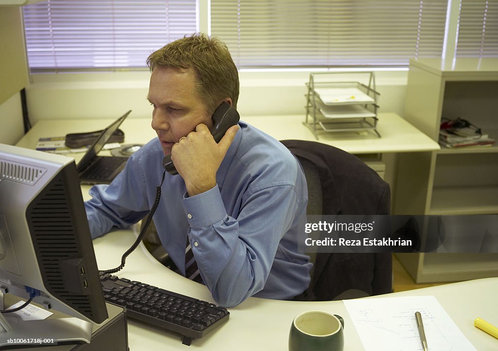 Businessman on phone at desk in office