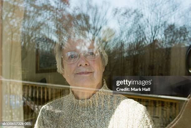 senior woman looking out of window - old woman by window stock pictures, royalty-free photos & images