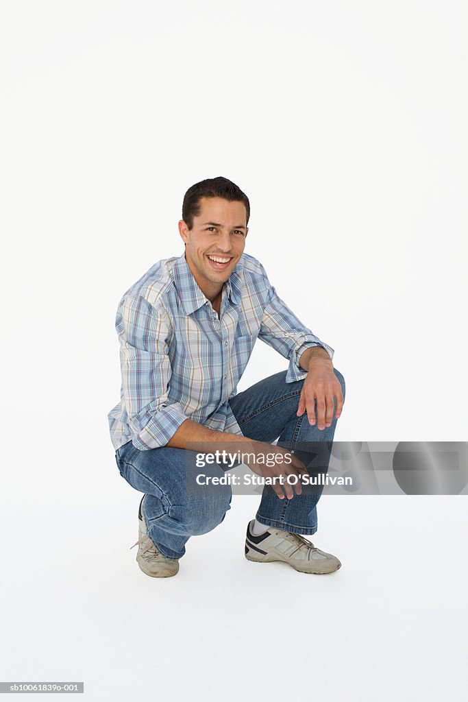 Portrait of young man squatting, smiling