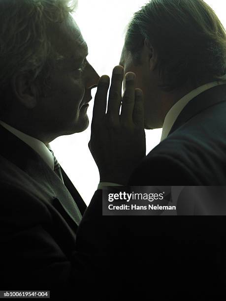 businessman whispering another businessman, close-up - gossip foto e immagini stock