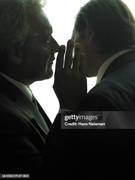 businessman whispering another businessman, close-up - rumor stockfoto's en -beelden