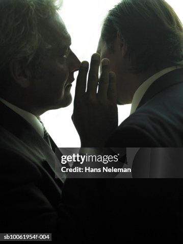 Businessman whispering another businessman, close-up