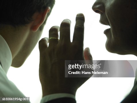 Businessman whispering another businessman, close-up
