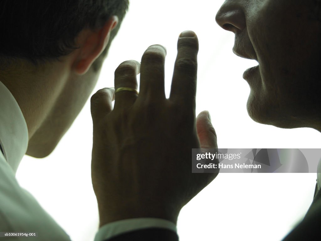 Businessman whispering another businessman, close-up