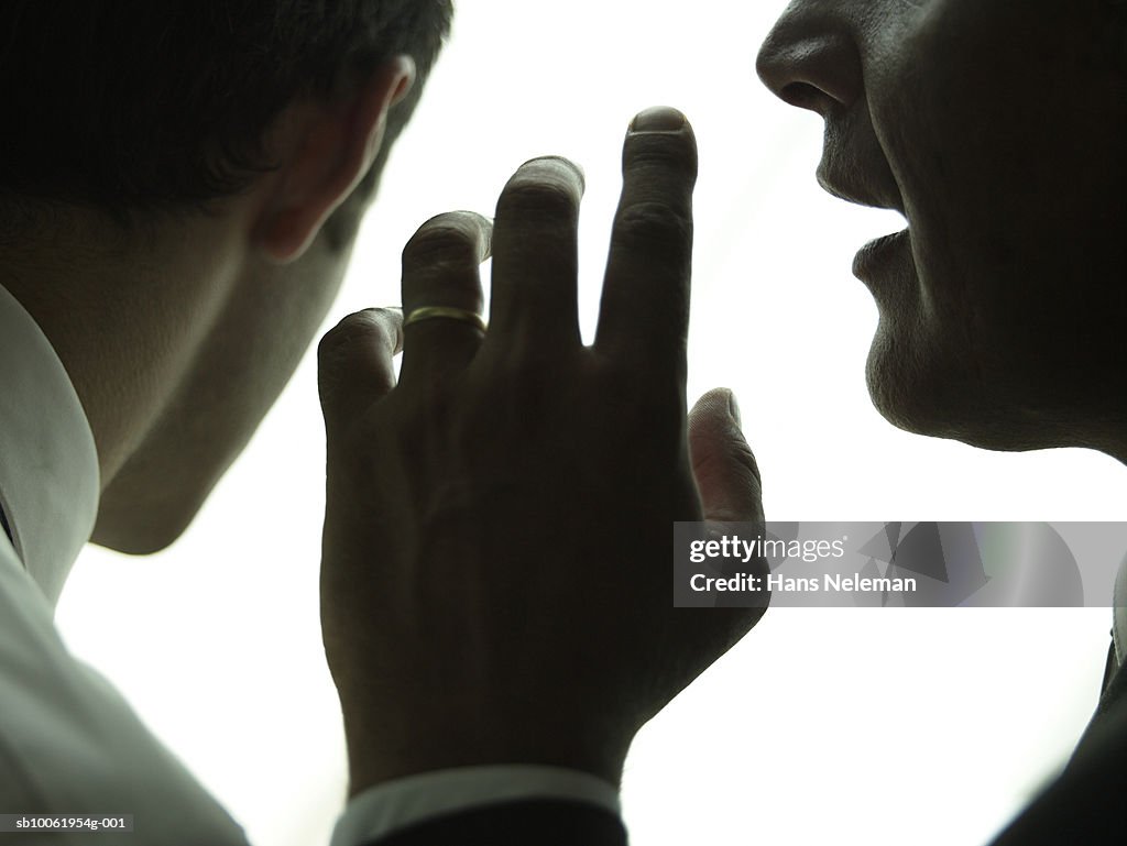 Businessman whispering another businessman, close-up