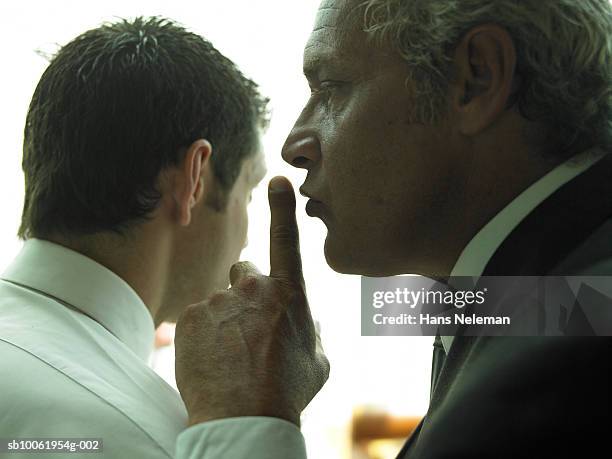 businessman warning another businessman to keep quiet, close-up - stilte stockfoto's en -beelden