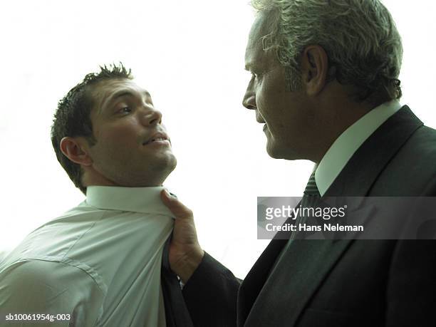 mature businessman gripping young businessman's collar, close-up - collar stock pictures, royalty-free photos & images