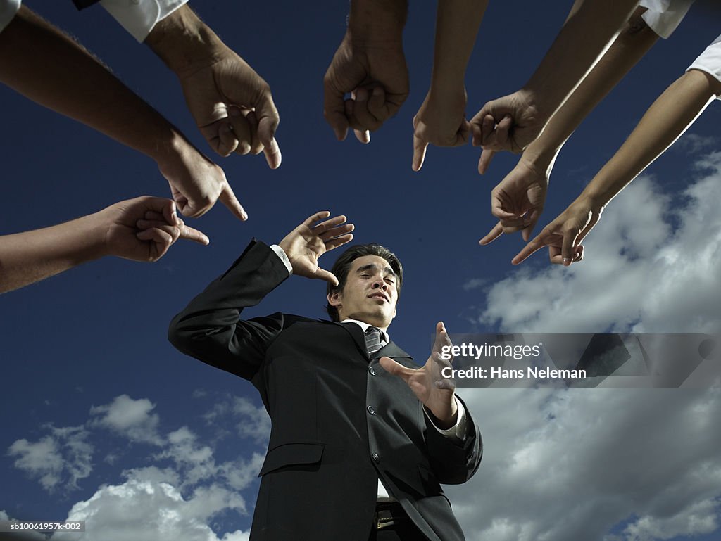 Businessman with fingers pointing at him, low angle view