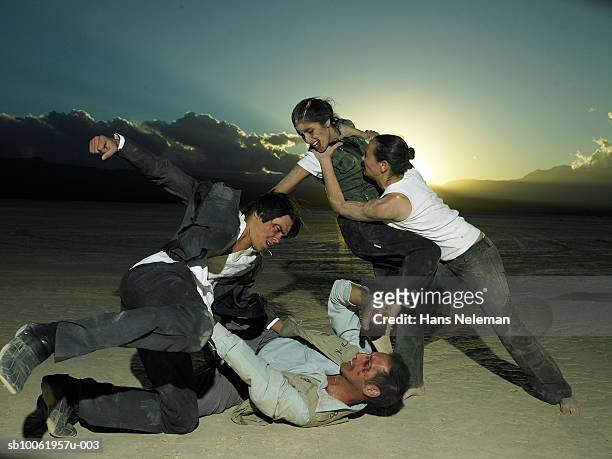 group of businesspeople fighting in desert at dusk - vechten stockfoto's en -beelden