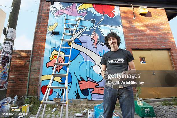 young man painting mural on wall, portrait - kunstenaar stockfoto's en -beelden