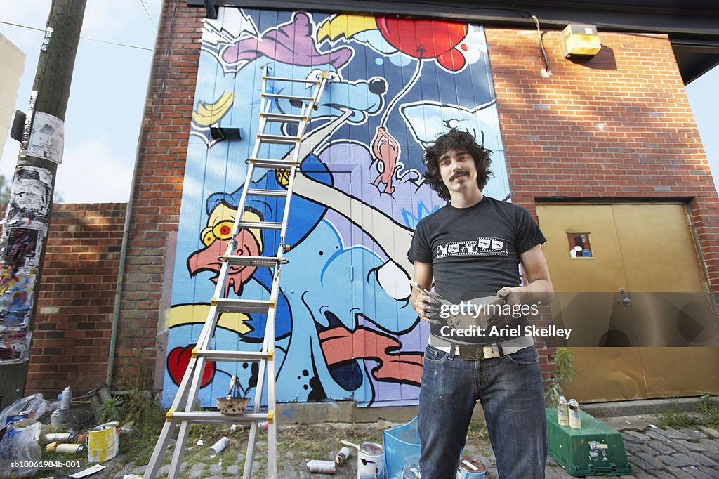 Young man painting mural on wall, portrait