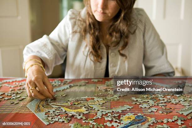 woman doing jigsaw puzzle in home - puzzle stock-fotos und bilder
