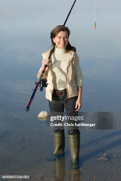 woman with fishing rod standing in lake, portrait, elevated view - ankle deep in water - fotografias e filmes do acervo