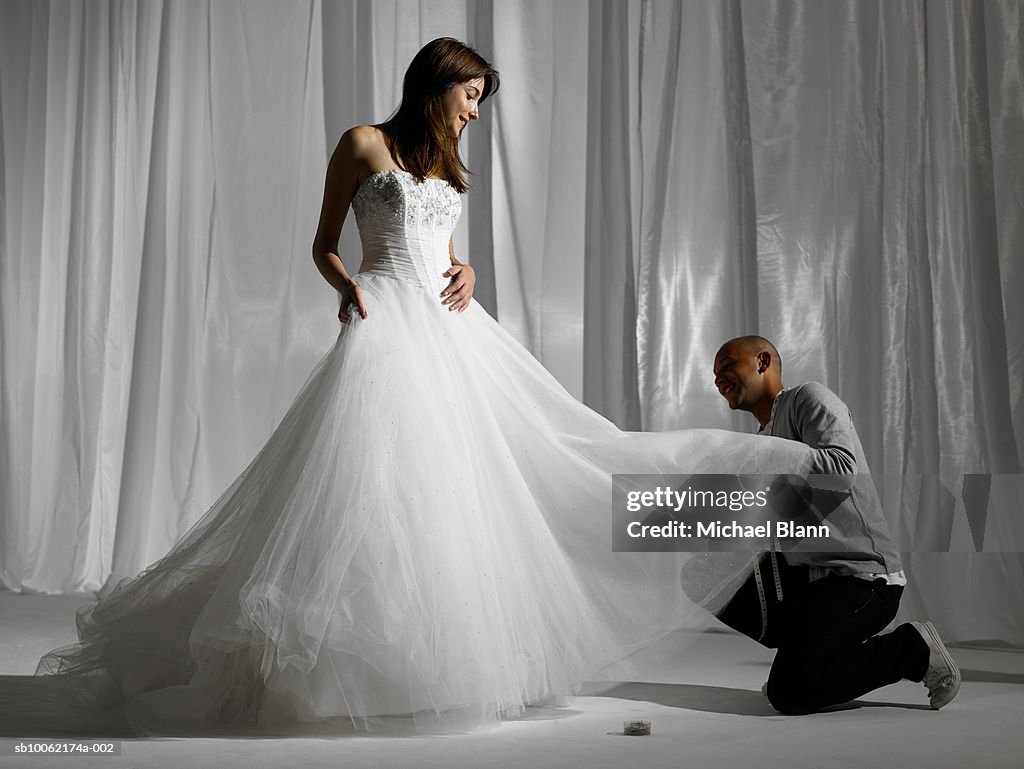 Young woman being measured in wedding dress, smiling