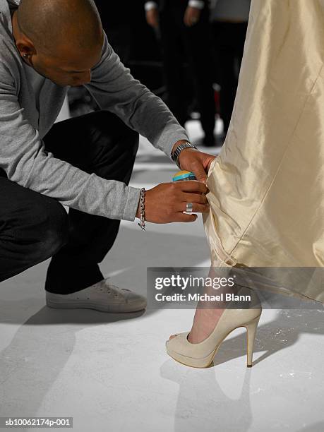 young man sewing hem of formal dress on stage. - hem stock pictures, royalty-free photos & images