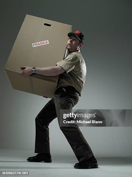 delivery man holding large box - side view carrying stock pictures, royalty-free photos & images