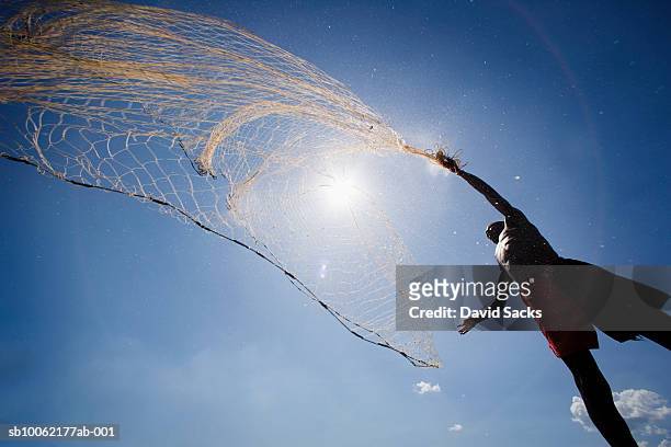 fisherman casting net, low angle view - fishing net stockfoto's en -beelden
