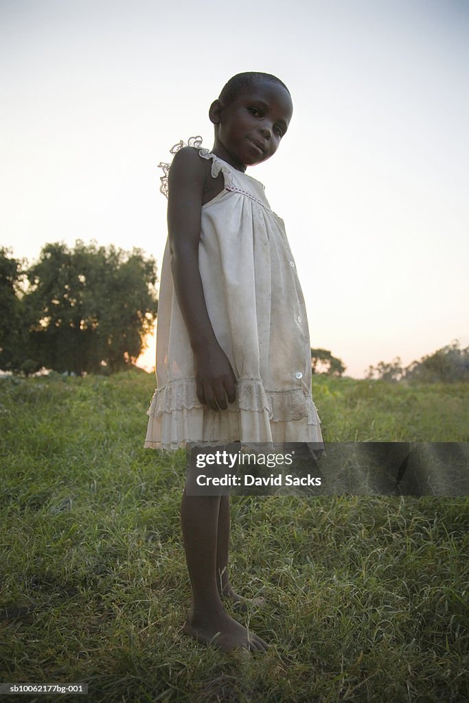 Girl (6-7) standing on grass, low angle view, portrait