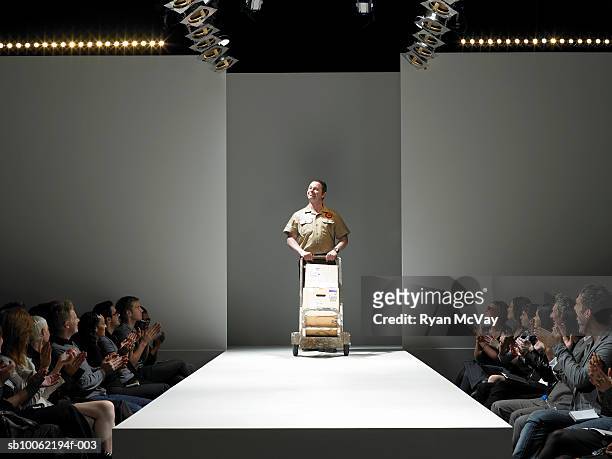 spectators applauding delivery man on catwalk - fashion show stock-fotos und bilder