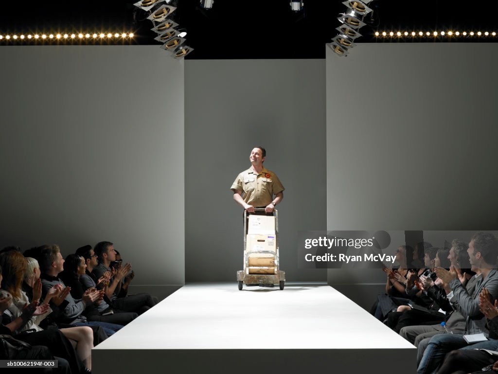 Spectators applauding delivery man on catwalk