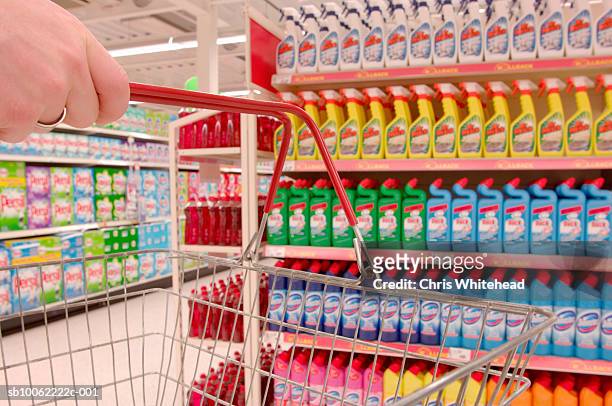 man holding basket by colourful detergents in supermarket - detersivi foto e immagini stock