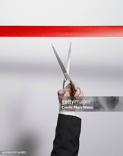 businessman using scissors to cut red tape, close-up of arm - administrative professional stock pictures, royalty-free photos & images
