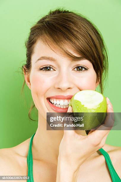 young woman holding green apple over face, smiling, portrait, head and shoulders - pomme croquée photos et images de collection