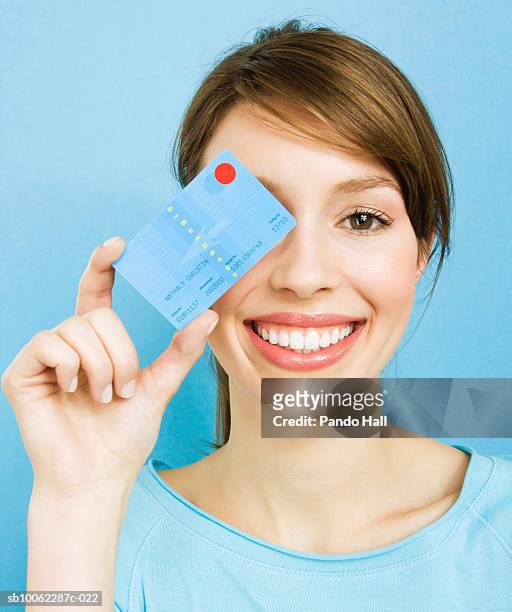 young woman holding credit card over eye, smiling, portrait, head and shoulders - credit card stock-fotos und bilder