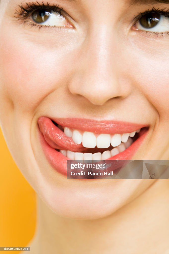 Young woman looking away and smiling, licking lips, close-up