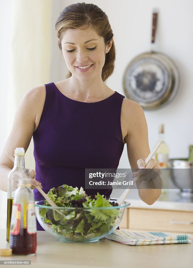 Young woman tossing salad, smiling
