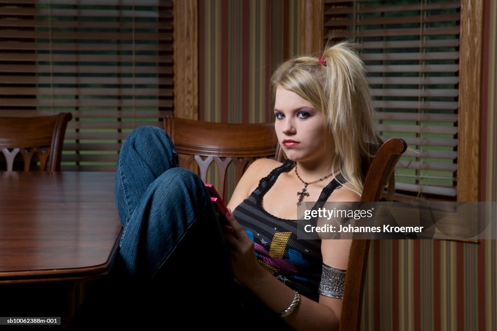 Teenage girl (14-15) dressed up gothic, sitting at table, portrait