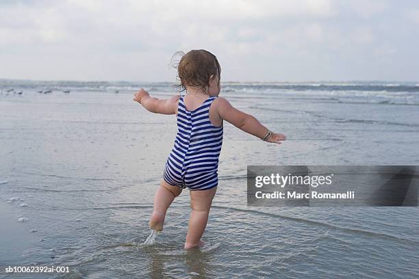 baby girl (9-12 months) on beach, rear view - one baby girl only fotografías e imágenes de stock