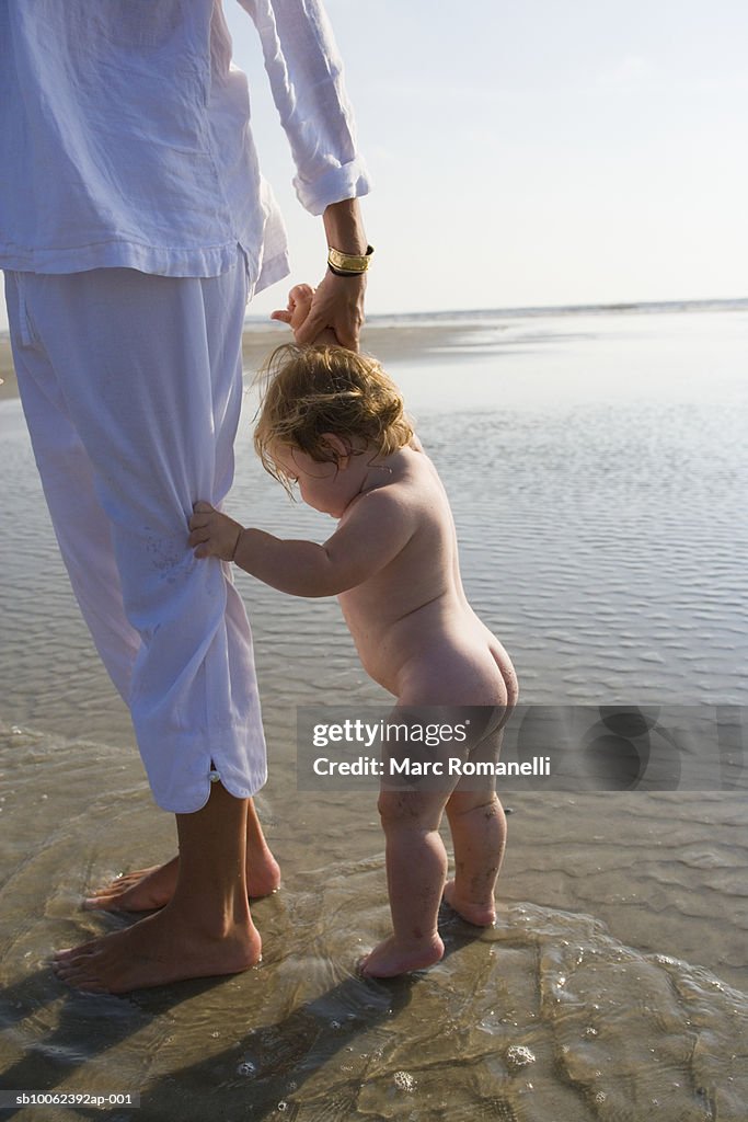 Mother with baby daughter (9-12 months) walking on beach