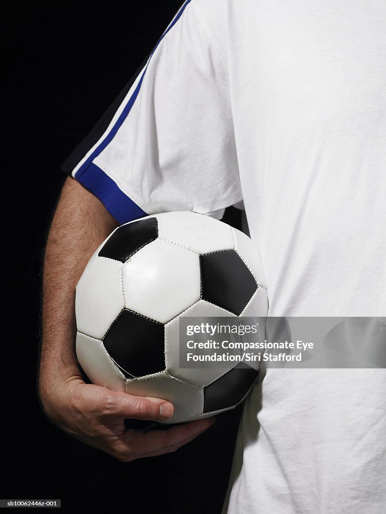 Man holding soccer ball, mid section