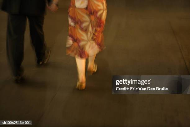 couple walking on street, low section, night - eric van den brulle stock-fotos und bilder