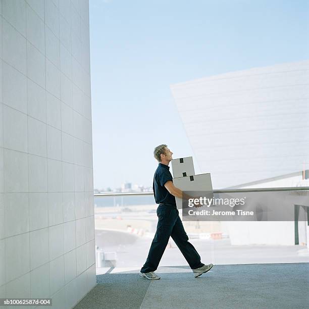 delivery man carrying boxes outside building, side view - side view carrying stock-fotos und bilder