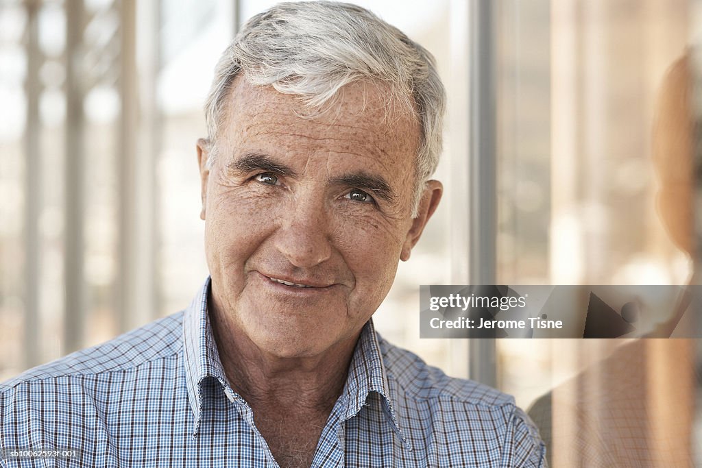 Senior man indoors, smiling, portrait, head and shoulders