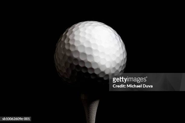 golf ball on tee against black background, close-up - ゴルフボール ストックフォトと画像