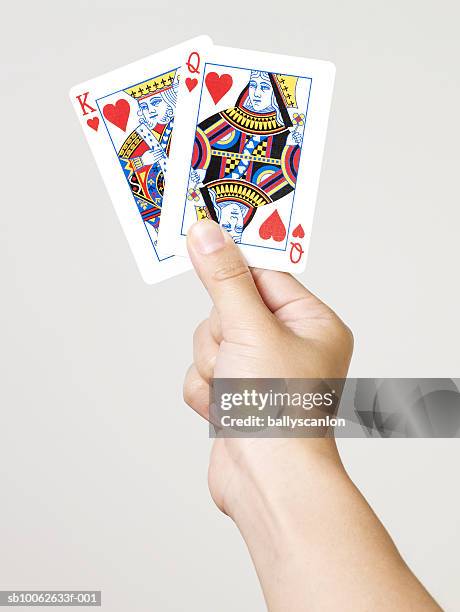 young woman holding king and queen of hearts playing cards, close-up of hand, studio shot - king card bildbanksfoton och bilder