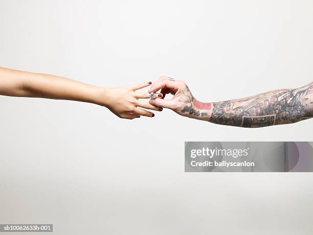 man with tattooed arm placing ring on finger of young woman, close-up of arms and hands - man tatoo bildbanksfoton och bilder