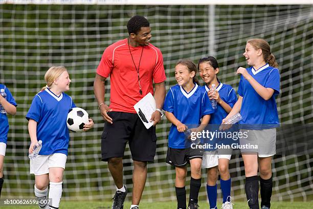 coach with girls (8-13) football team, smiling - coach stockfoto's en -beelden