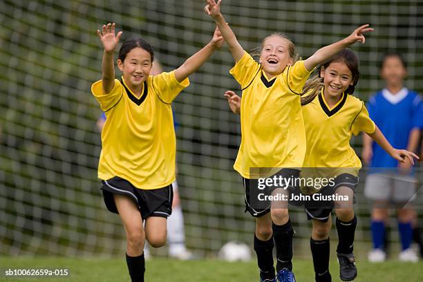 girls (8-11) playing football (differential focus) - schoolmeisje stockfoto's en -beelden
