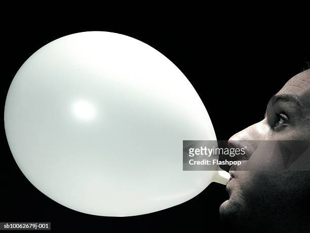 young man blowing up balloon, side view, close-up - encher imagens e fotografias de stock