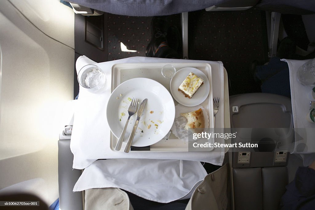 Plate and cutlery on tray table in airplane, overhead view