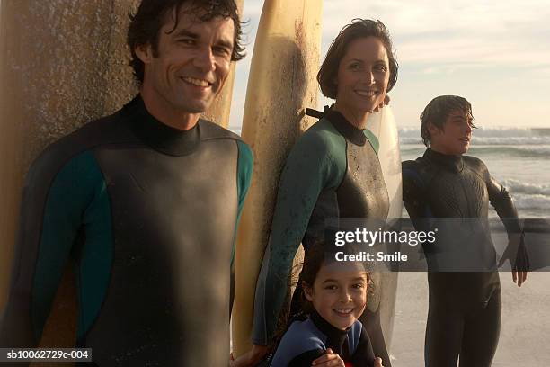 parents with son (14-15) and daughter (6-7) with surfboards on beach, smiling - junge 13 jahre oberkörper strand stock-fotos und bilder