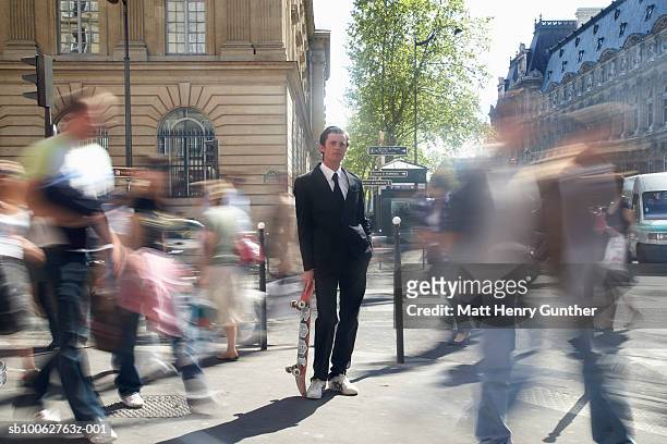 businessman holding skateboard in streets, blurred motion - scherpte stockfoto's en -beelden