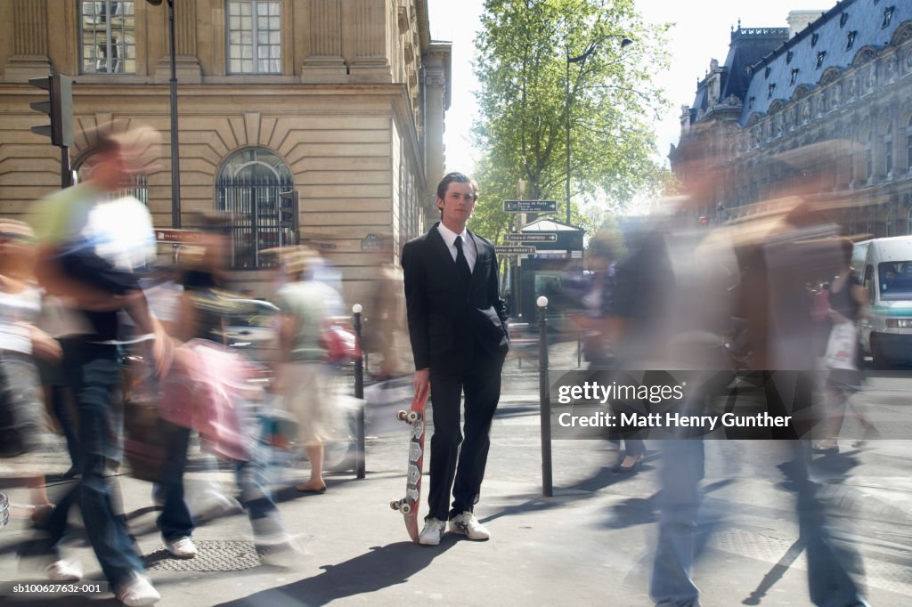 Businessman holding skateboard in streets, blurred motion