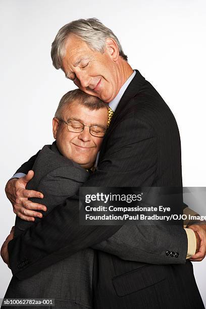 tall and short businessmen hugging, side view - fond studio stock pictures, royalty-free photos & images